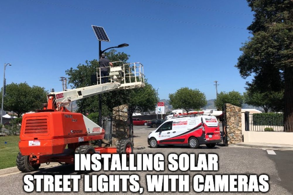 West Coast Security Inc. installing solar street lights with cameras from a lift